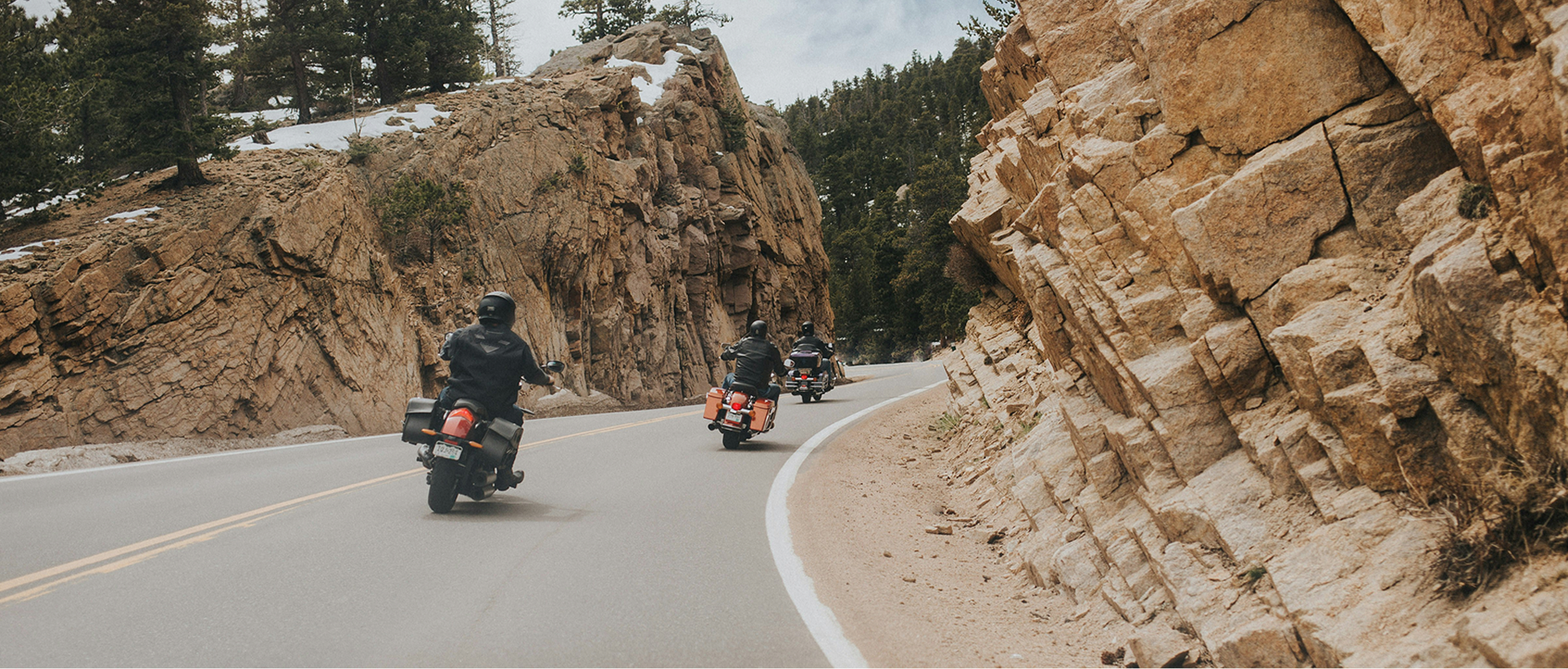 Group of bikers riding motorcycles together on a highway through scenic countryside