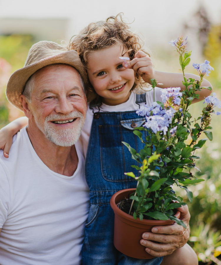 Grandfather and child smiling while holding flowers outdoors