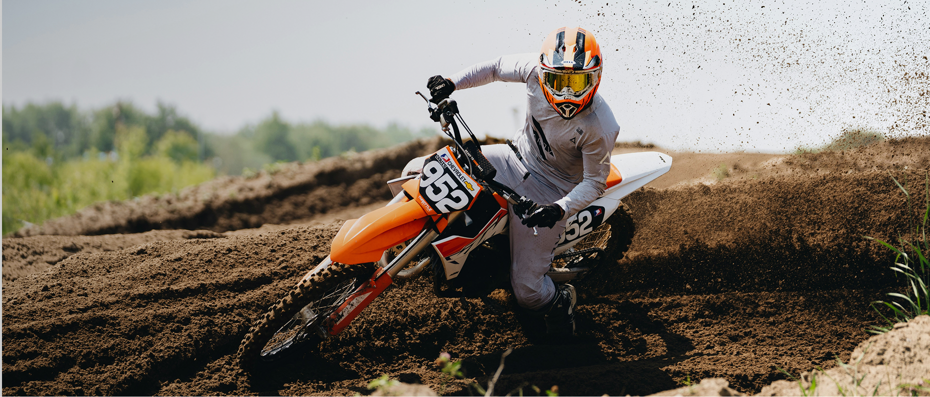 Offroad biker riding through rough terrain with dust flying around