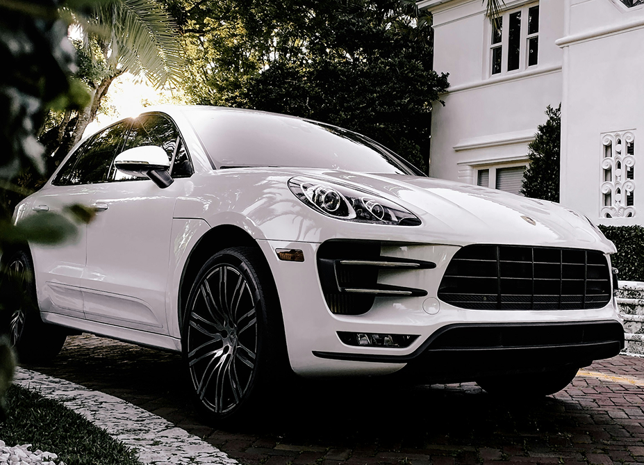 High-end white Porsche vehicle standing in the driveway of a luxurious modern home